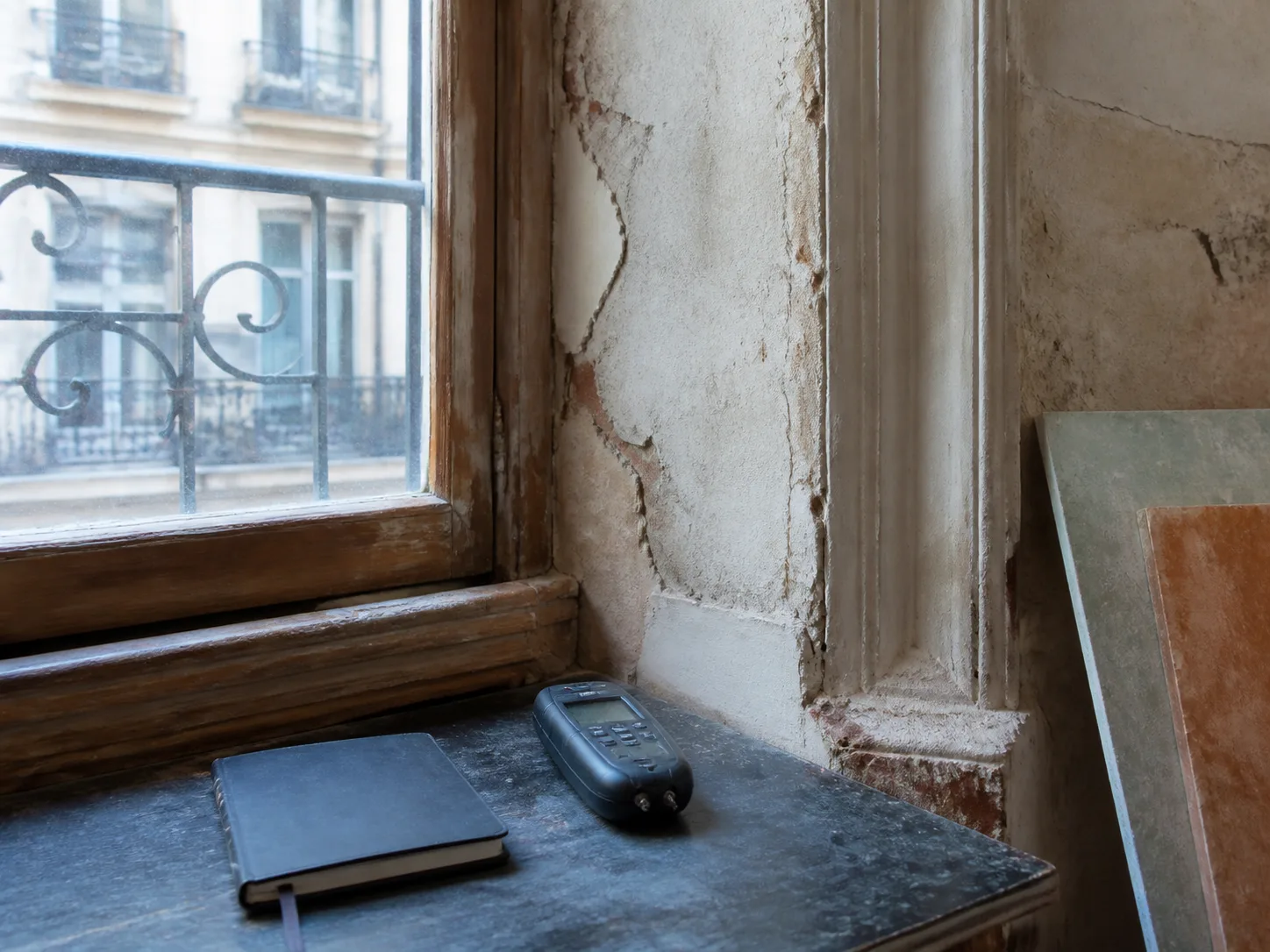 Ancienne fenêtre en bois, enduit fissuré et appareil de mesure sur une table