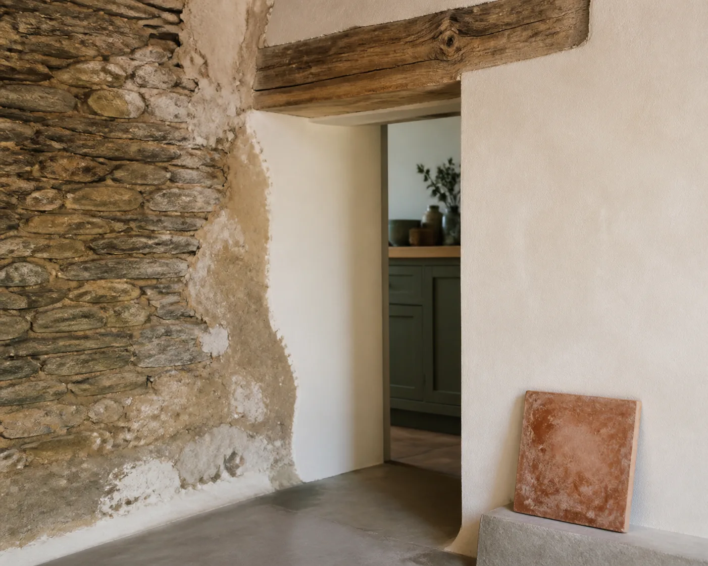 Mur ancien en pierre et enduit à la chaux autour d’un linteau en bois